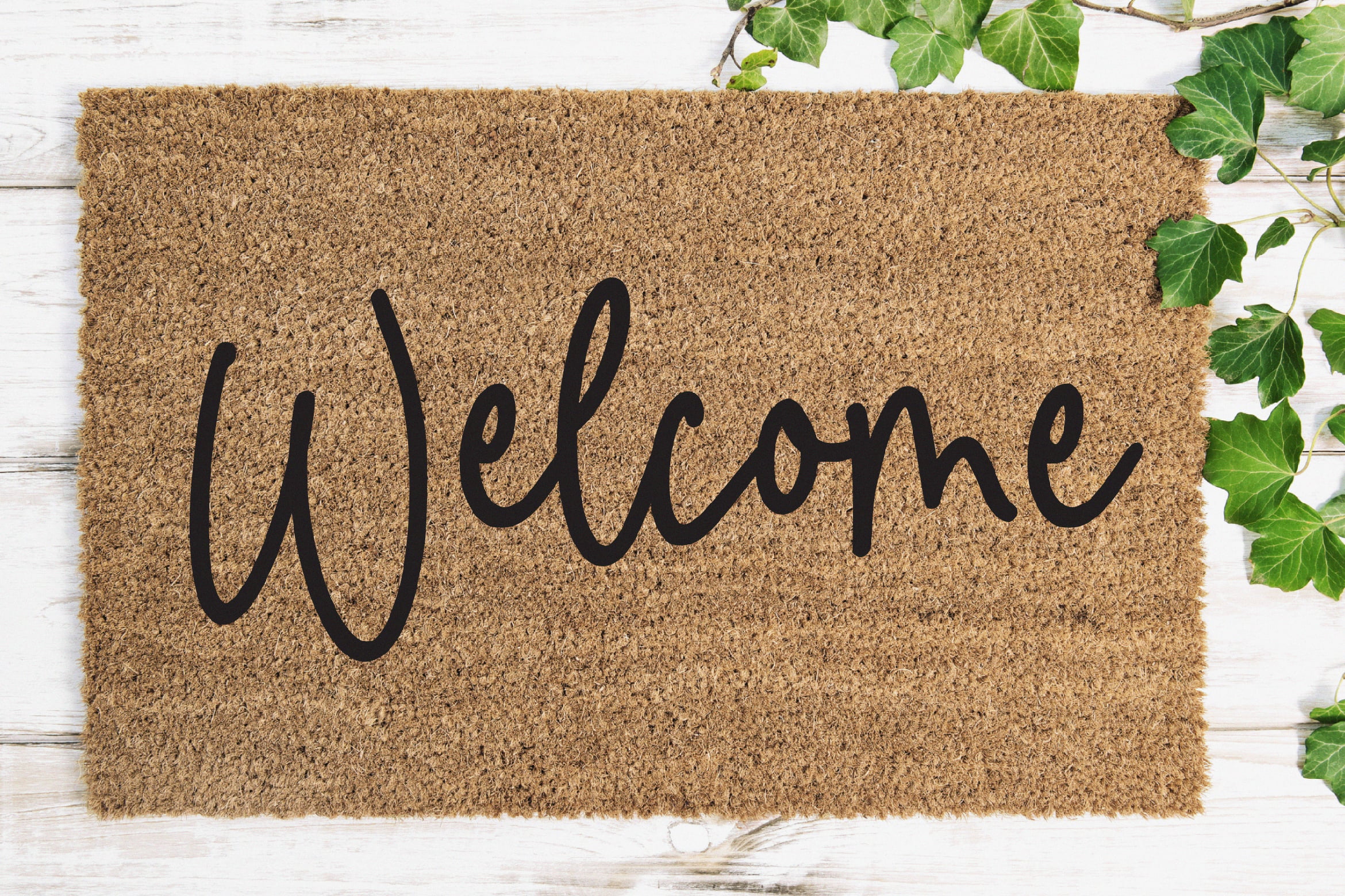 Welcome doormat mockup with green ivy on white wooden background ideal for graphic designers digital assets typography templates home decor design.