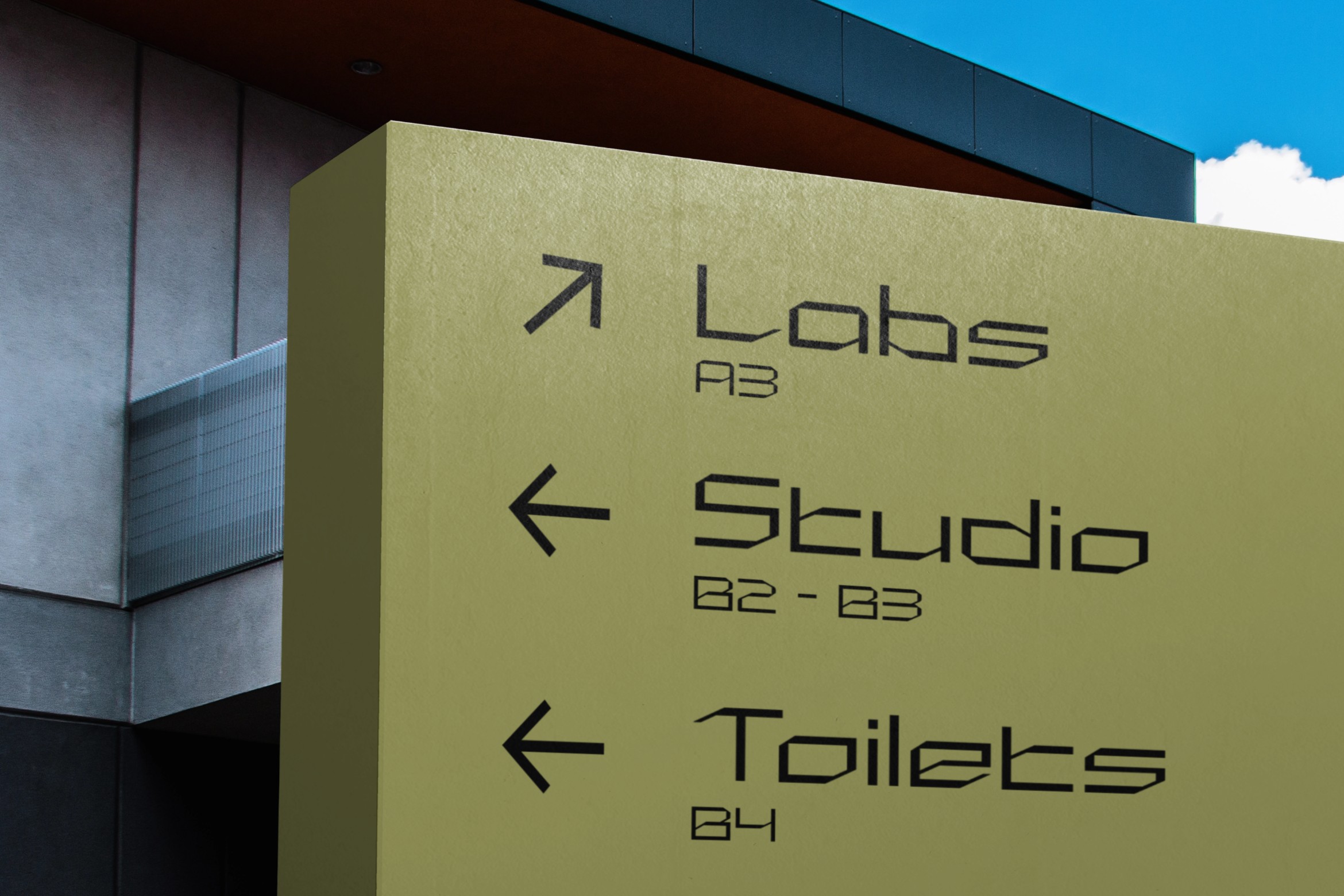 Yellow building wayfinding sign with Labs, Studio, Toilets directional text