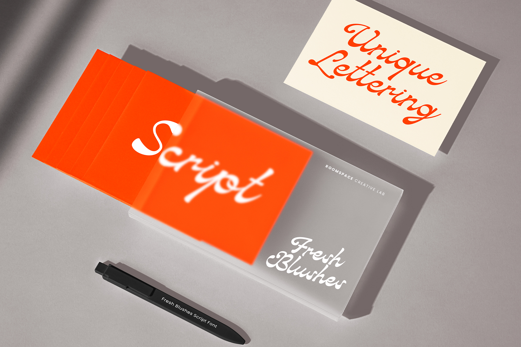 Orange business cards with Fresh Blushes script font on gray surface