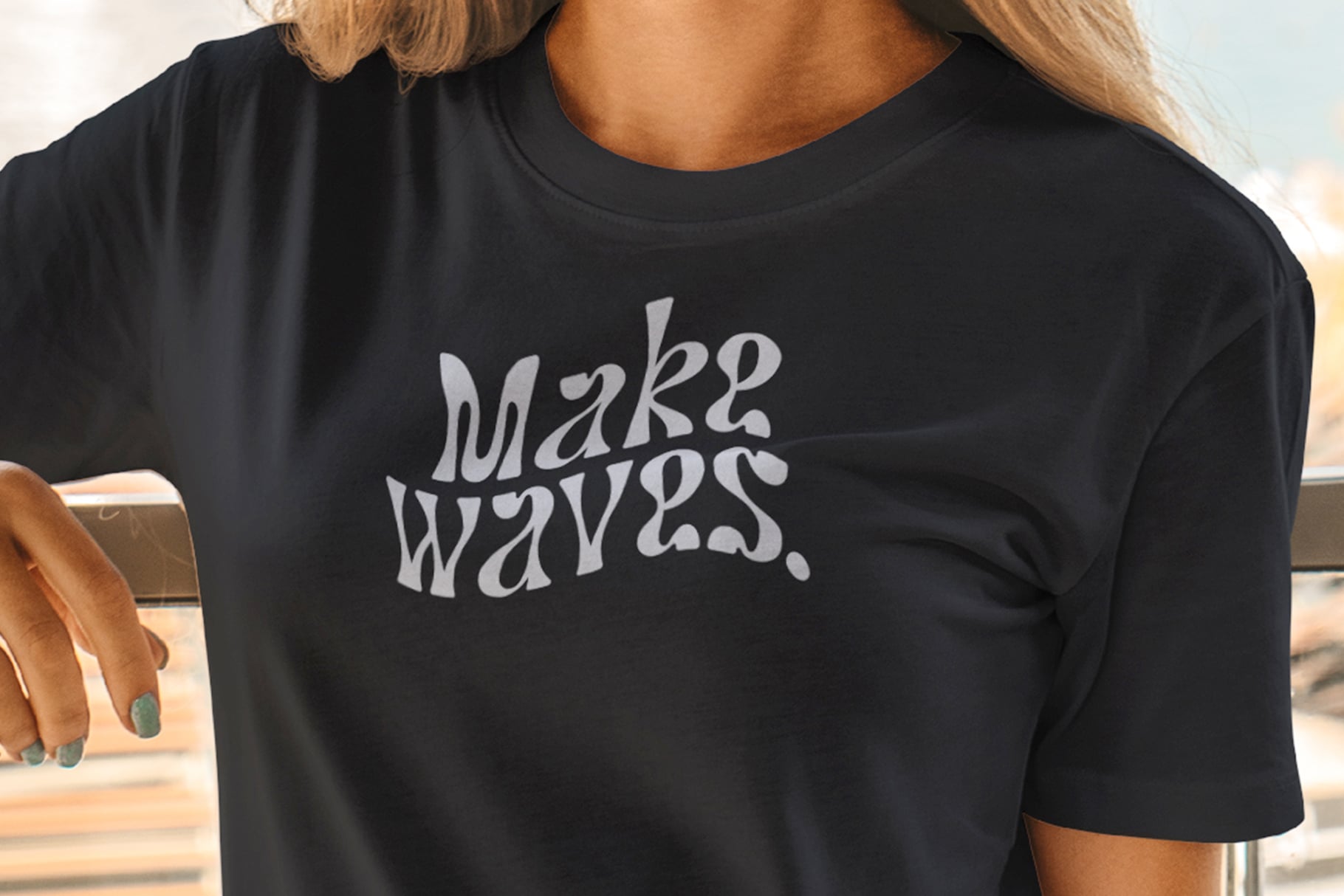 Make Waves text printed on black tee shirt worn by person outdoors