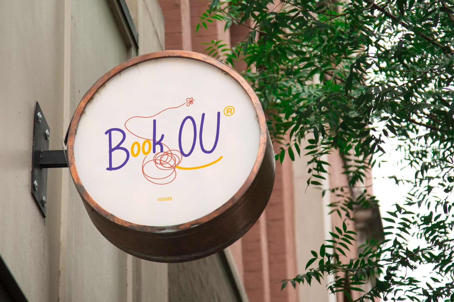 Circular wooden storefront sign with BookOU logo in purple, yellow, red squiggles
