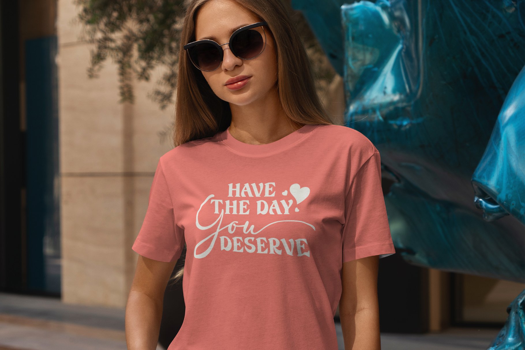 Woman in coral tee with have the day you deserve text design