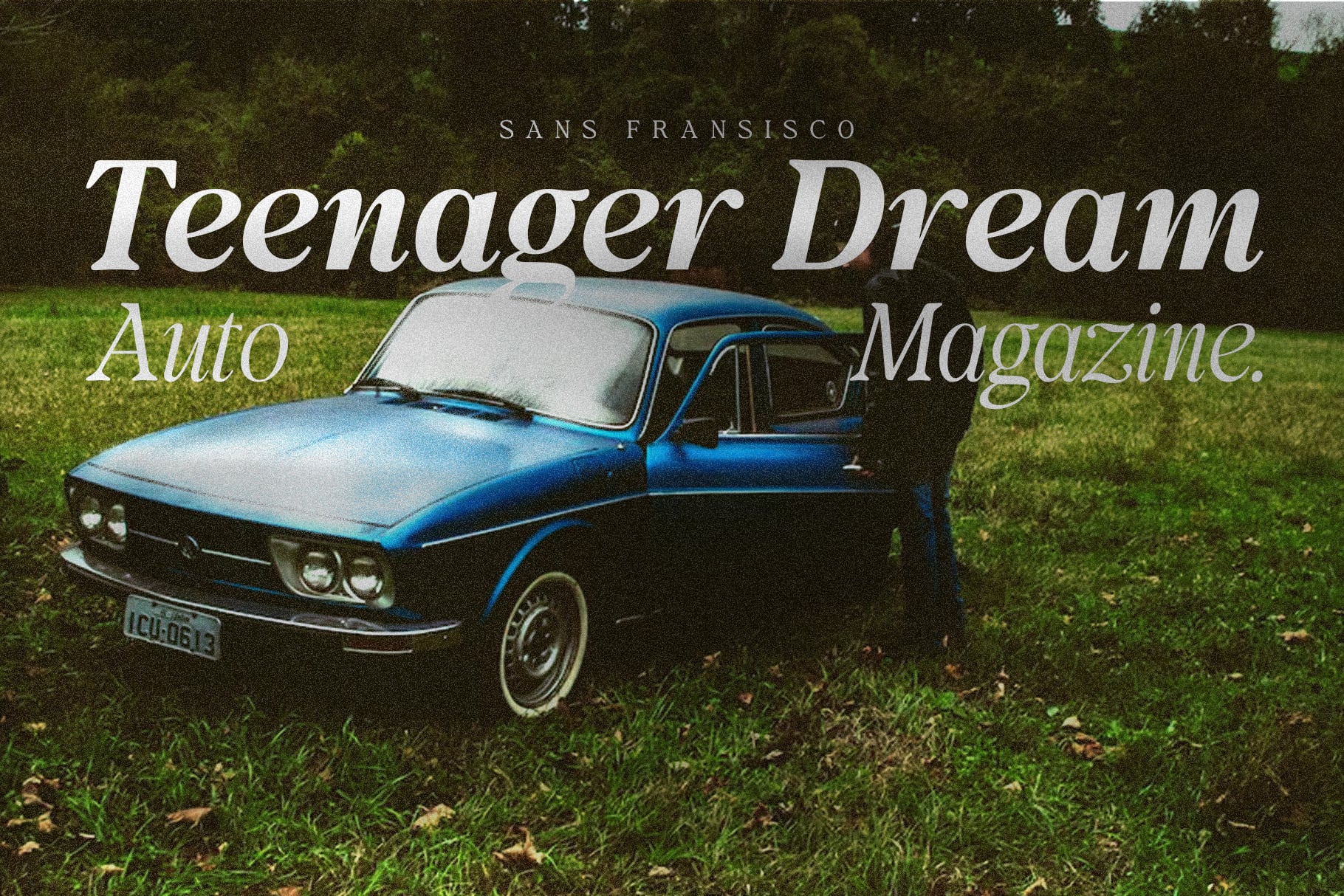 Vintage blue car with open door on grass under trees with magazine title overlay