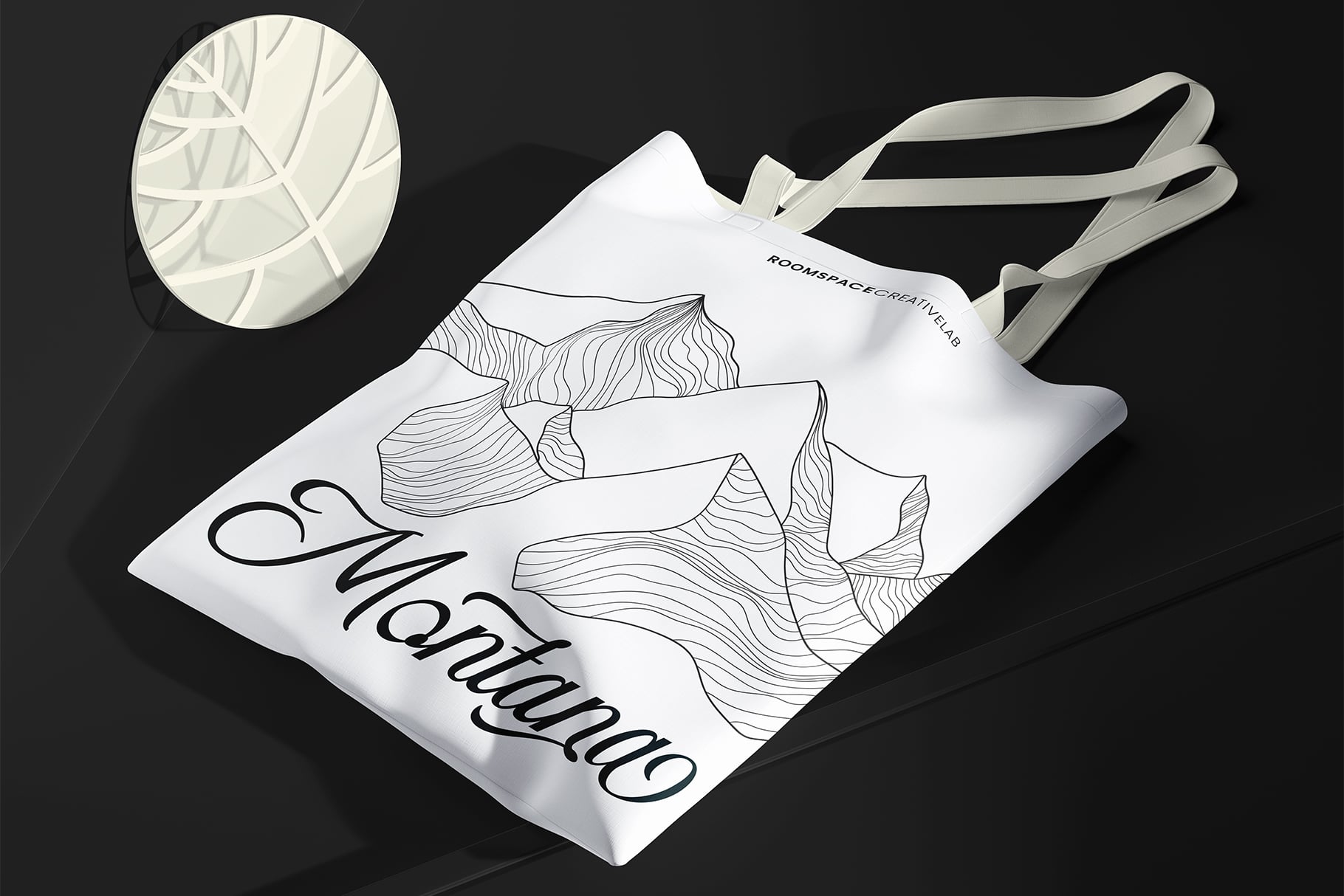 White canvas tote bag mockup with line art botanical illustration on dark background