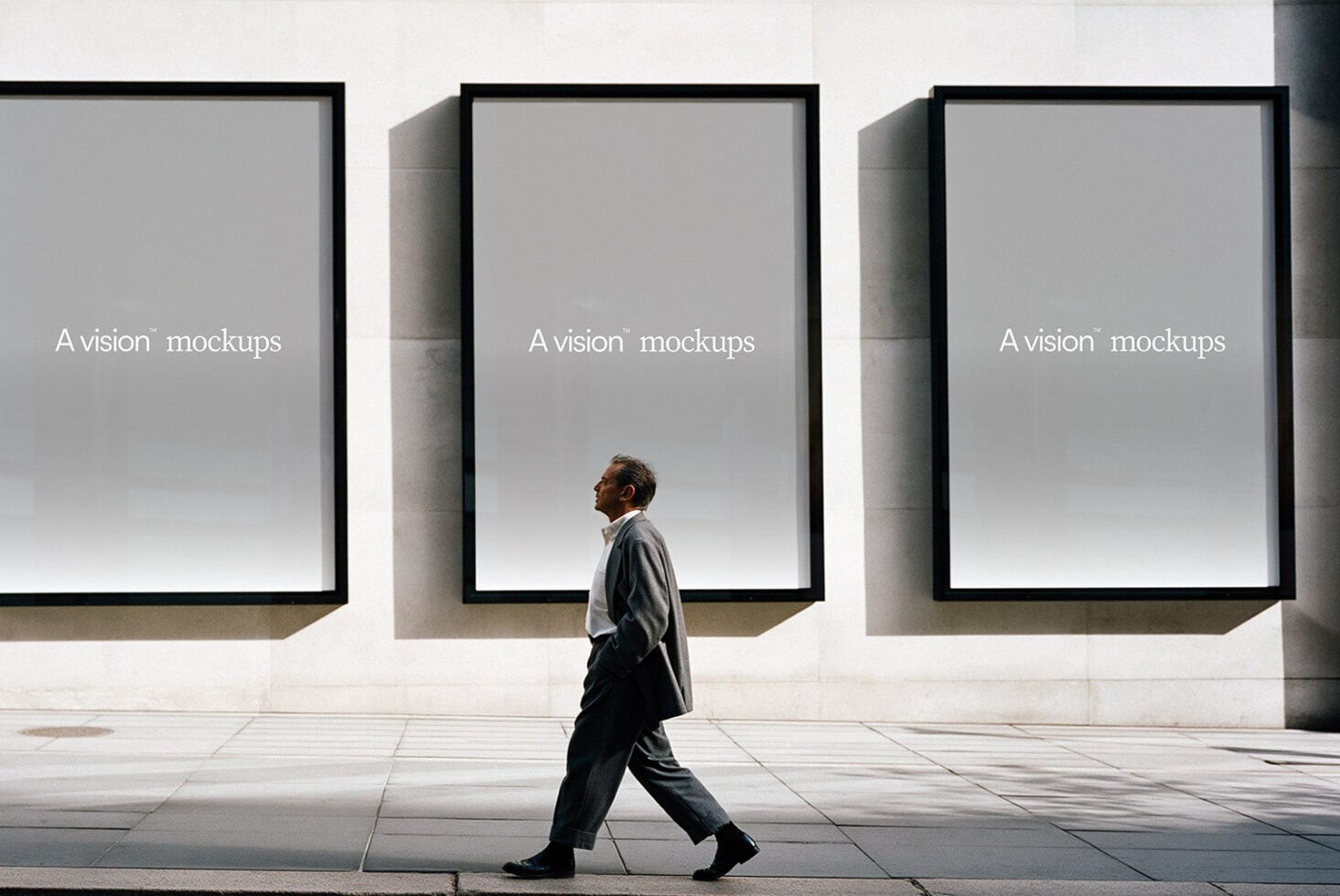 Man walking past three large black-framed windows on concrete plaza