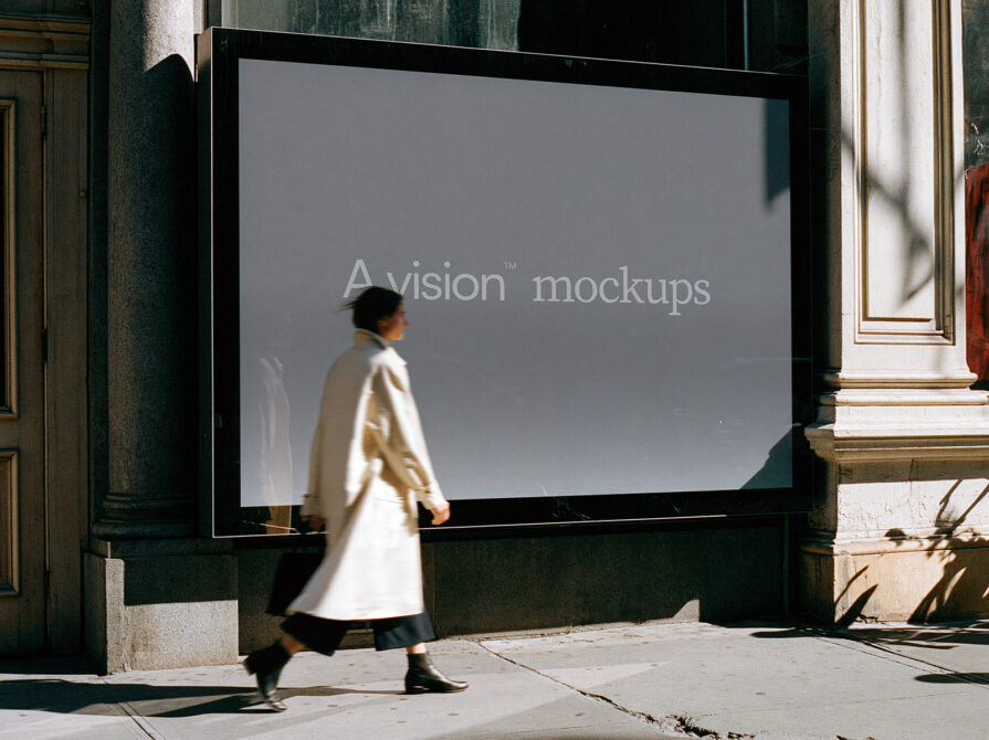 Person walking past large storefront window display with gray screen showing text