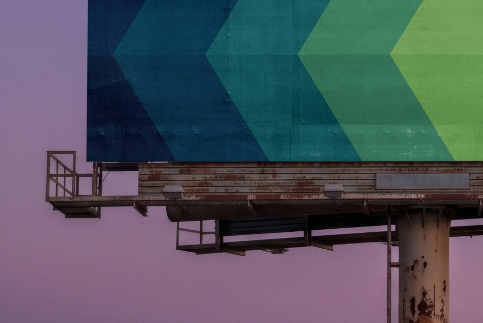 Weathered billboard with chevron gradient against purple sky
