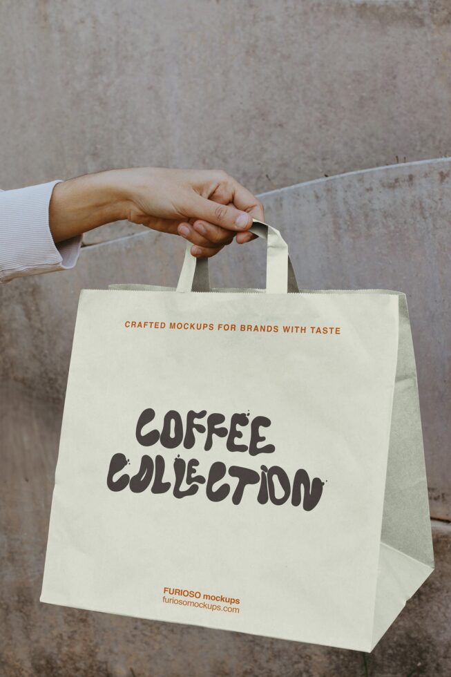 Cream tote bag with dark lettering held against gray wall backdrop