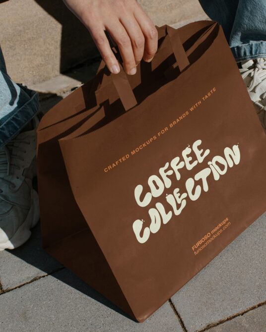Brown paper shopping bag held by person showing Coffee Collection in cream lettering