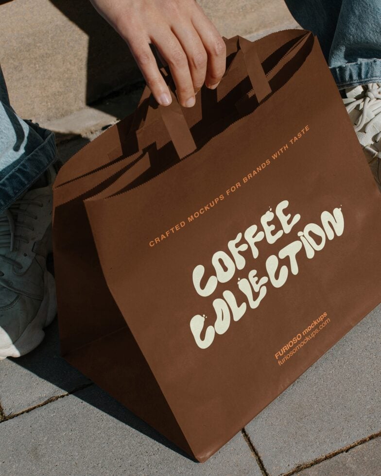 Brown paper shopping bag held by person showing Coffee Collection in cream lettering
