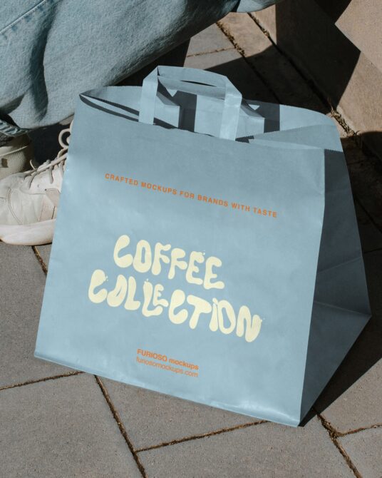 Light blue paper shopping bag with Coffee Collection text displayed outdoors on pavement