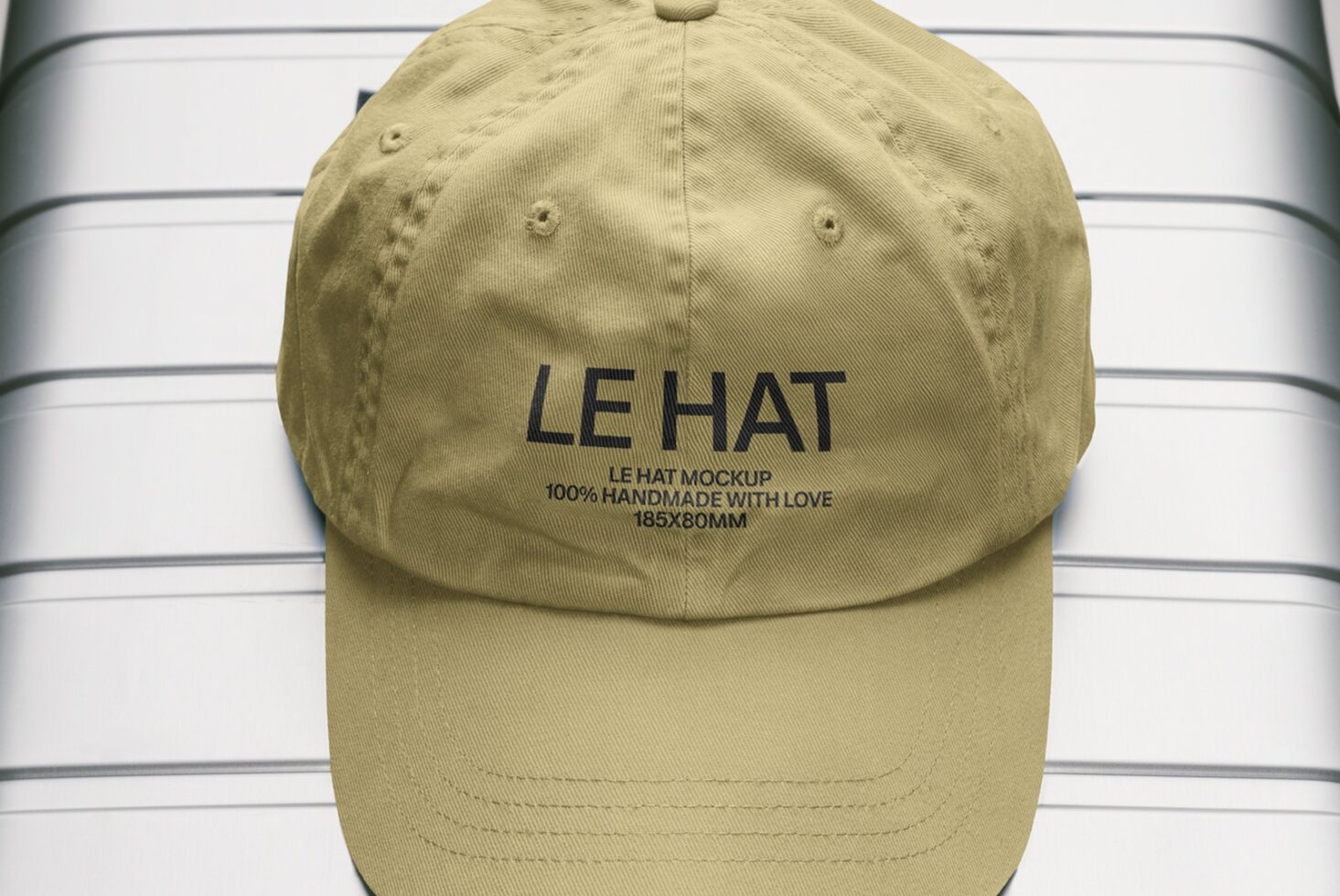 Beige baseball cap front view with embroidered branding on striped backdrop