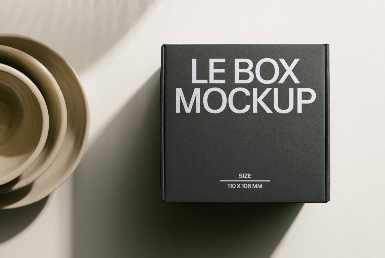 Dark charcoal box mockup in overhead composition with ceramic bowls in shadows
