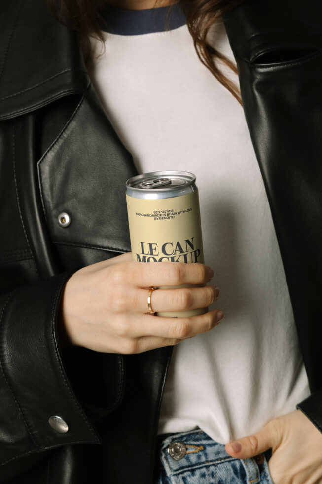 Woman in black leather jacket holding yellow aluminum can mockup with LE CAN branding