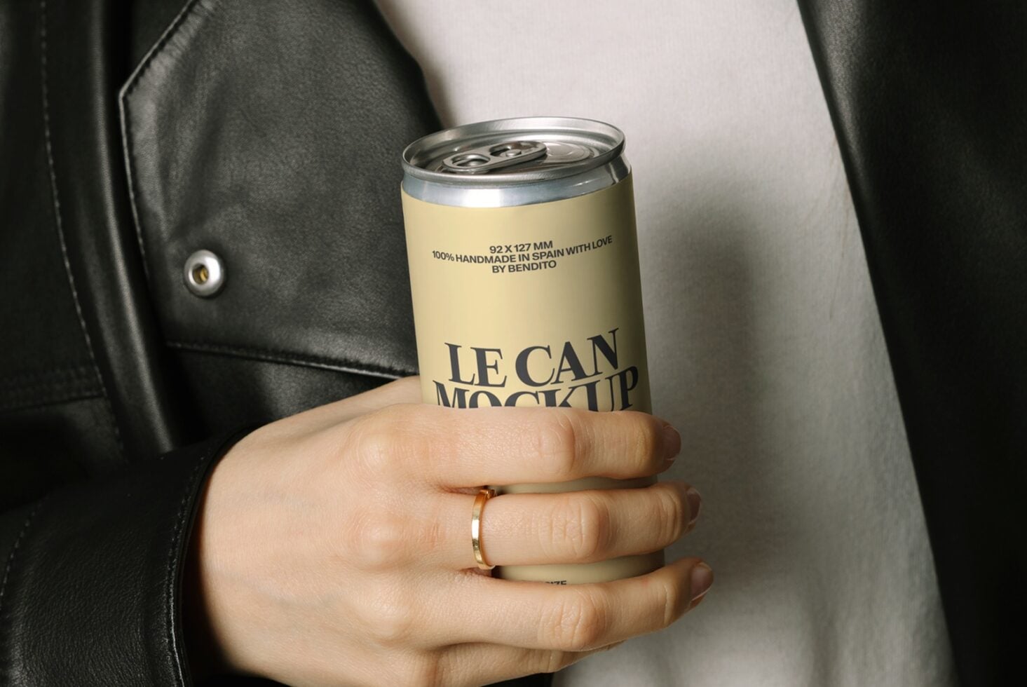 Hand holding yellow aluminum beverage can mockup against white shirt, black jacket
