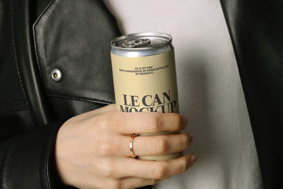Hand holding yellow aluminum beverage can mockup against white shirt, black jacket