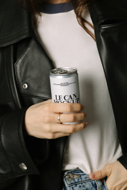 Woman in black leather jacket holding white aluminum can mockup with LE CAN branding