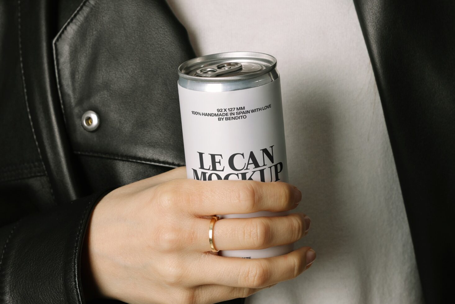 Hand holding white aluminum beverage can mockup against white shirt, black jacket