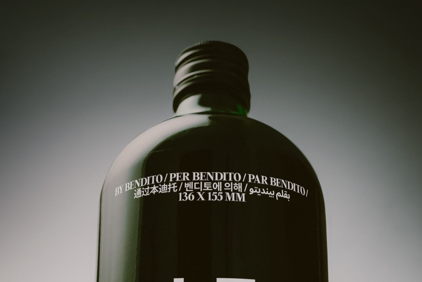 Dark glass bottle mockup with multilingual label text, minimal studio lighting