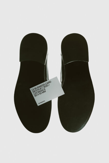 Business card mockup laid on black shoe soles, overhead view