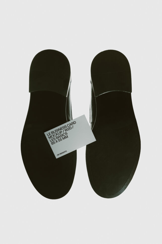 Business card mockup laid on black shoe soles, overhead view