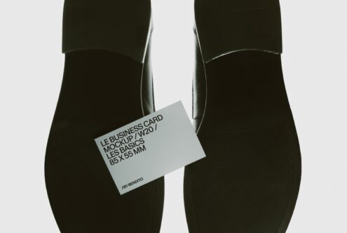 Business card mockup held between two black cylindrical objects, minimal styling