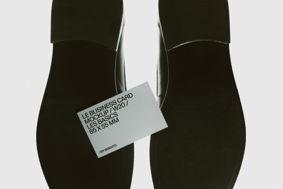 Business card mockup held between two black cylindrical objects, minimal styling