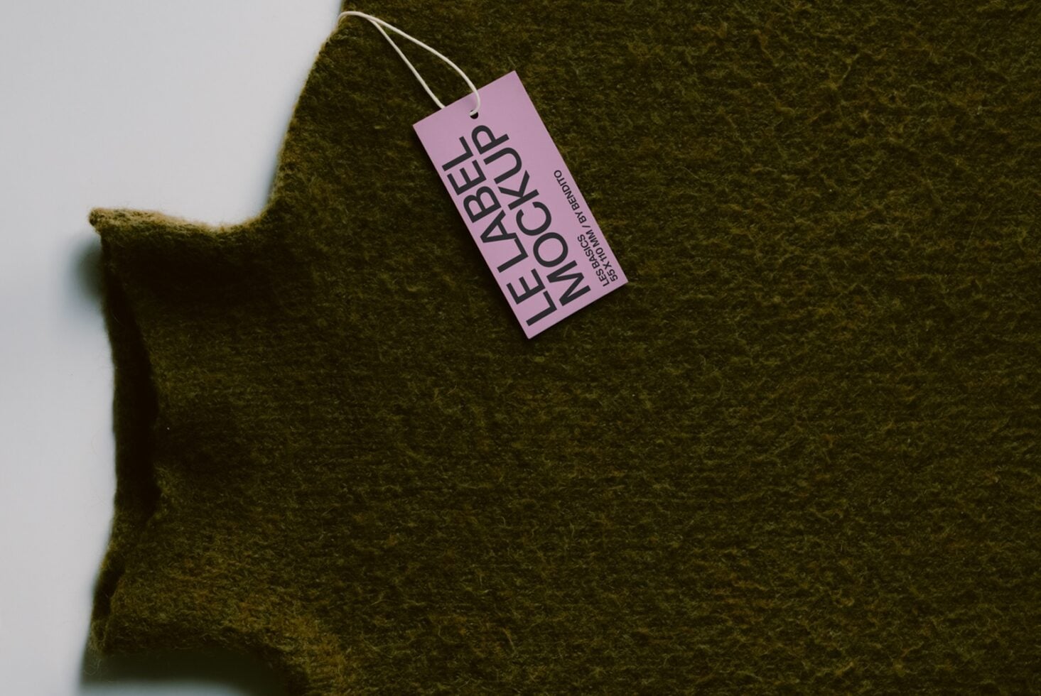 Pink hang tag on chunky olive wool fabric with natural folds