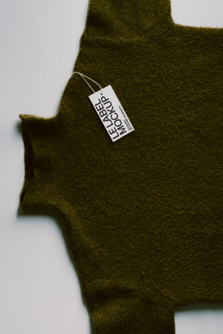 Olive wool sweater with white hang tag mockup on neutral background