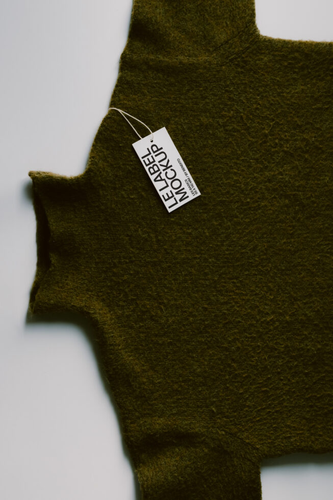 Olive wool sweater with white hang tag mockup on neutral background