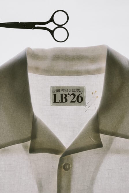 Woven shirt with sewn-on label mockup, scissors overhead, minimal styling