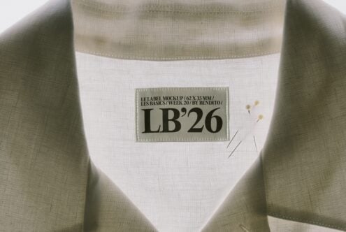 Clothing label mockup on sage ribbed fabric with stitched edges, showing 62x35mm tag design