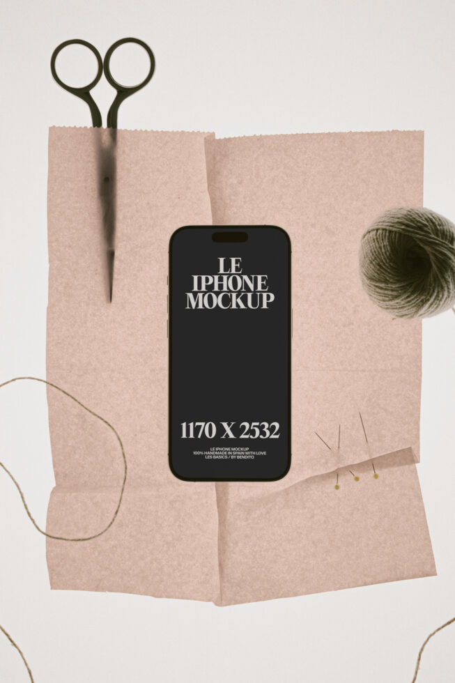iPhone mockup on crumpled kraft paper with scissors, yarn ball, minimal styling overhead shot