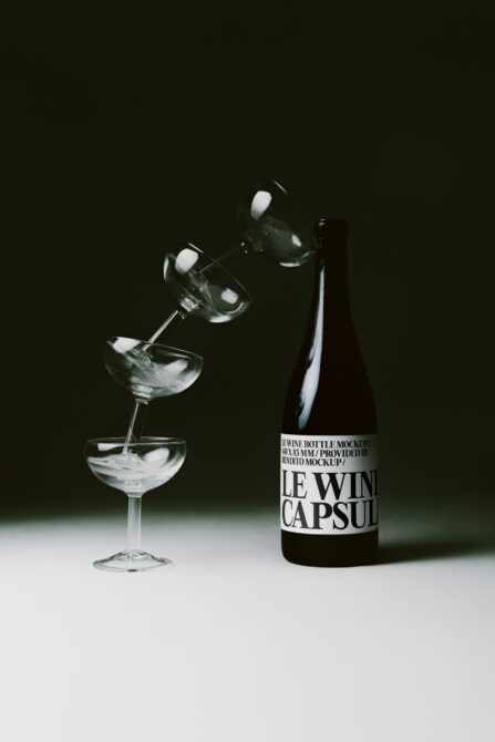 Wine bottle mockup with pouring glasses in dramatic studio lighting on dark background