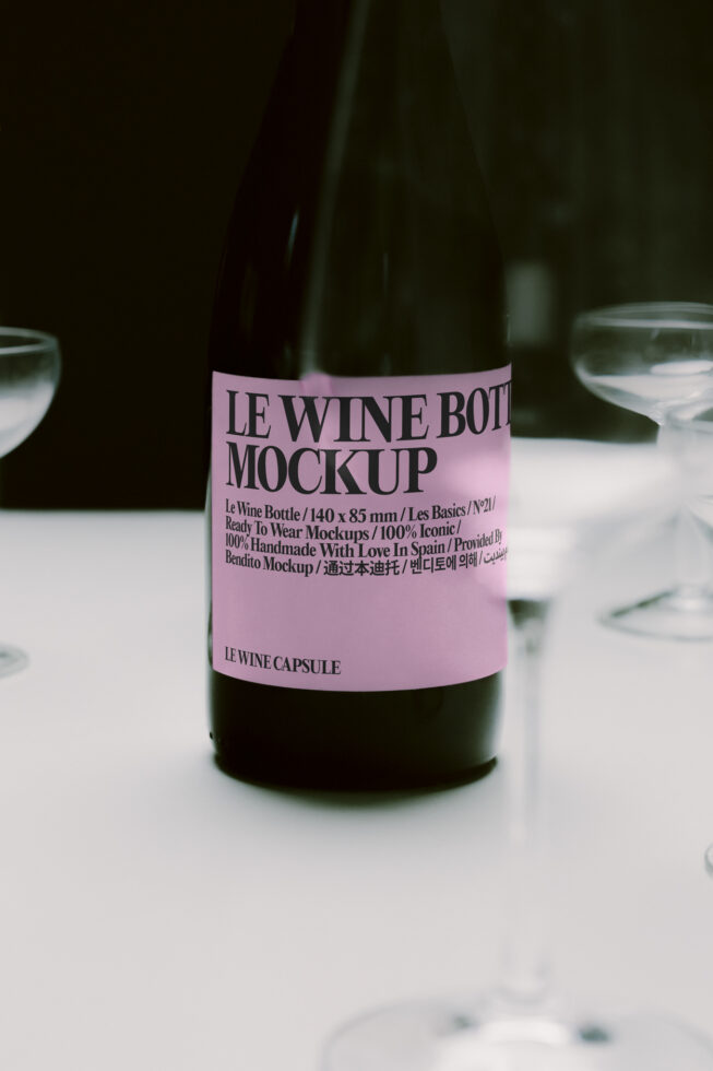Wine bottle mockup with pink label on table with glasses