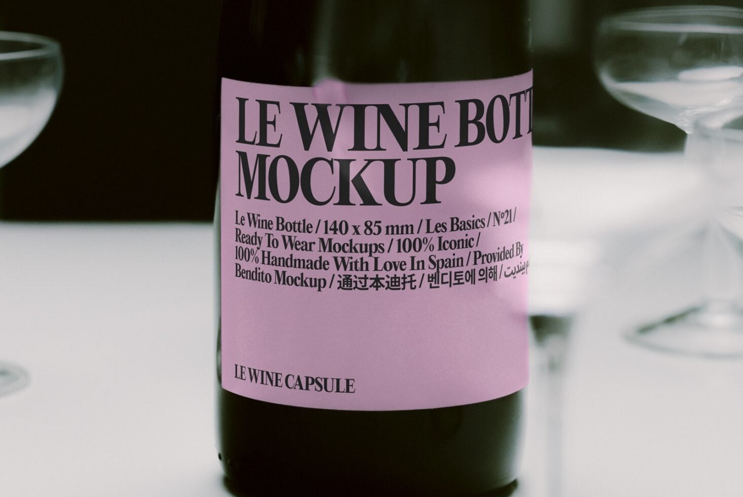 Wine bottle with pink label on table surrounded by water glasses in soft focus
