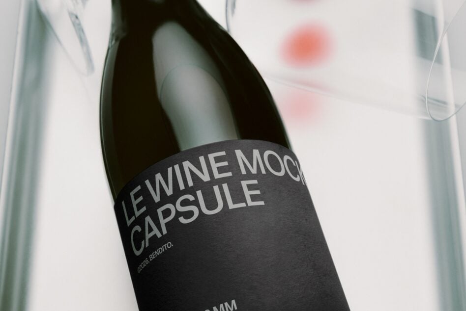 Wine bottle with black label on white surface, soft blurred background with glass