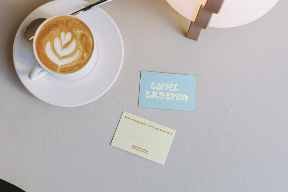 Cappuccino with foam art beside blue business card mockup on white surface