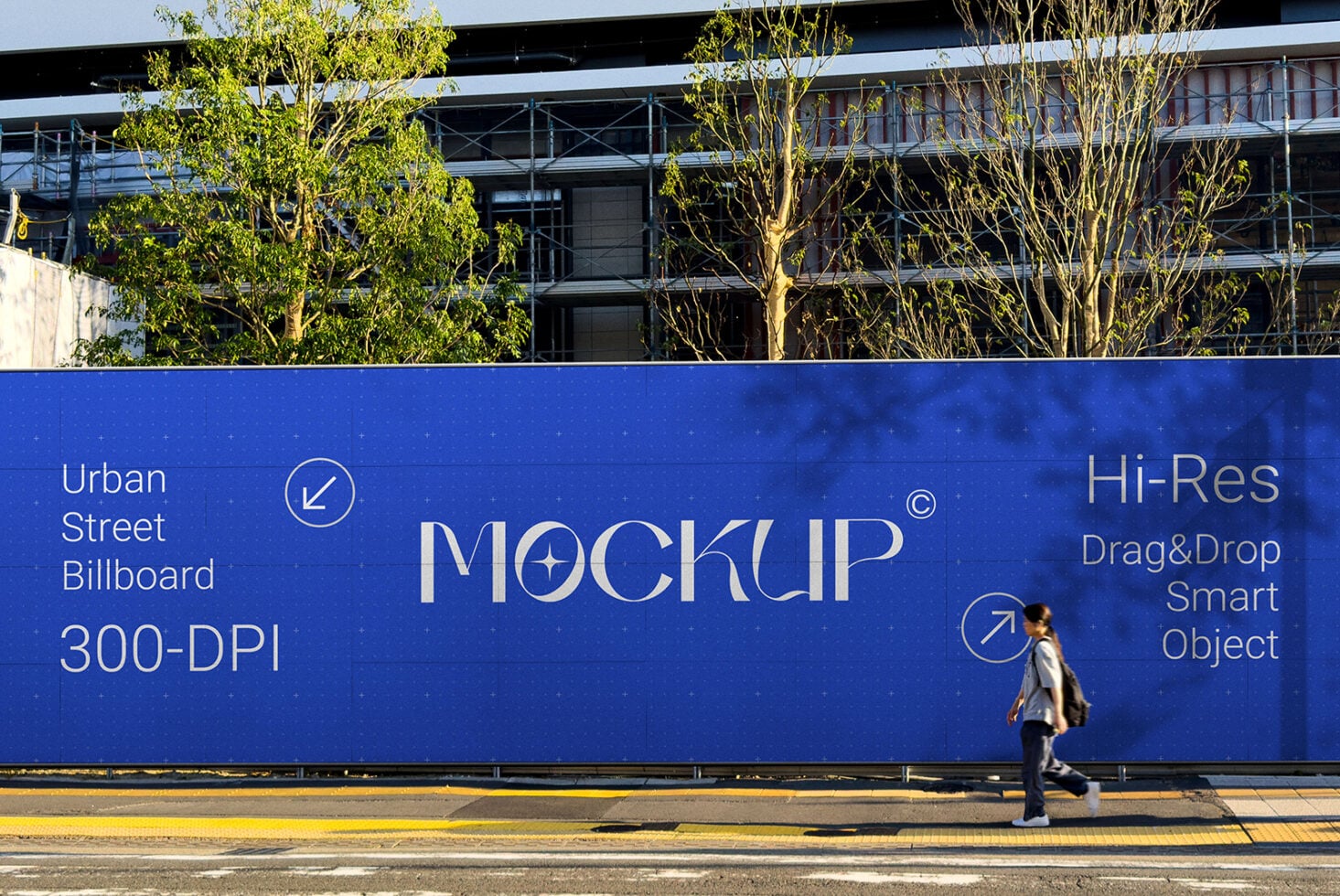 Bright blue street billboard mockup with person walking by, industrial building backdrop, sunny day
