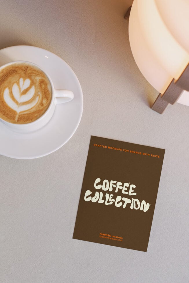 Flat lay of coffee cup with latte art, lamp, brown card mockup below