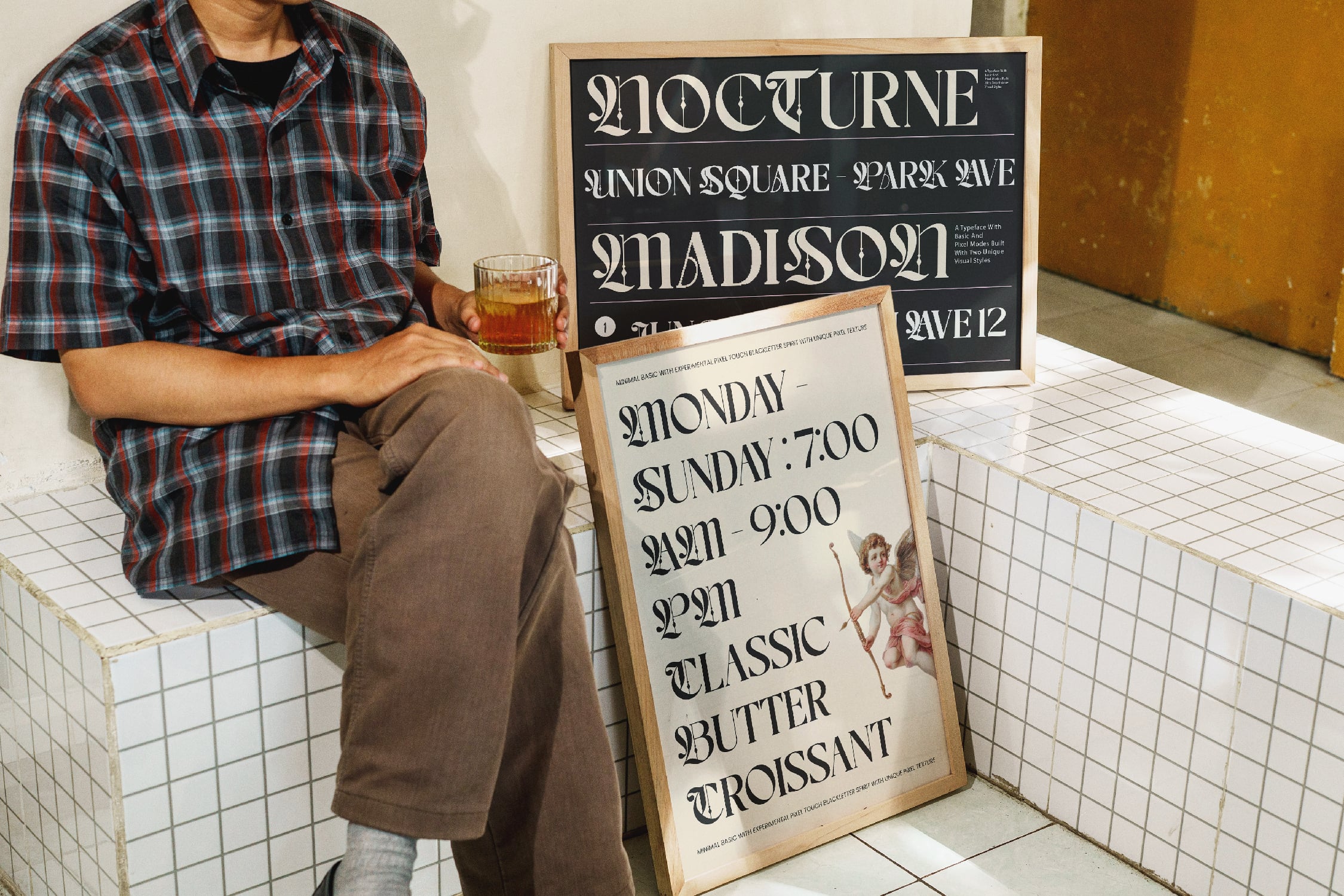 Cafe signage mockup showing man holding drink with wooden framed black board displaying serif typeface sample text