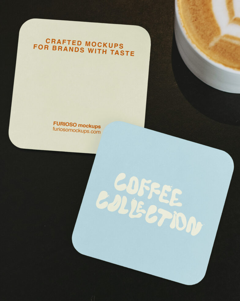 Cream, blue coasters next to latte with latte art on dark surface