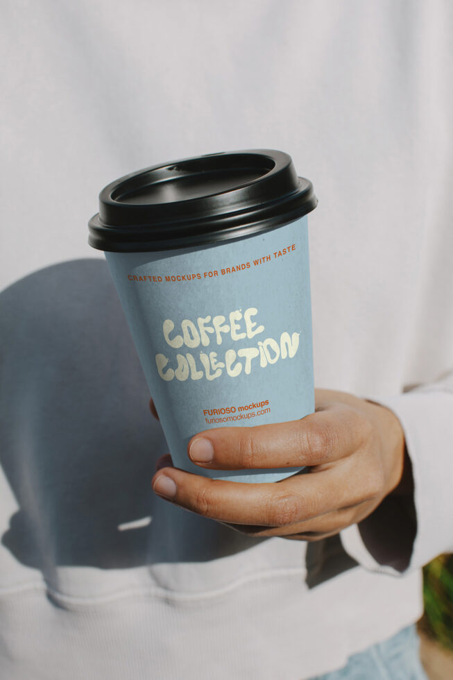Light blue to-go cup with black lid held in hand, cream colored Coffee Collection typography
