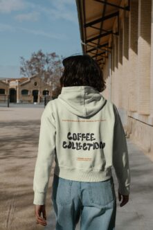 Cream hoodie back worn outside against brick architecture
