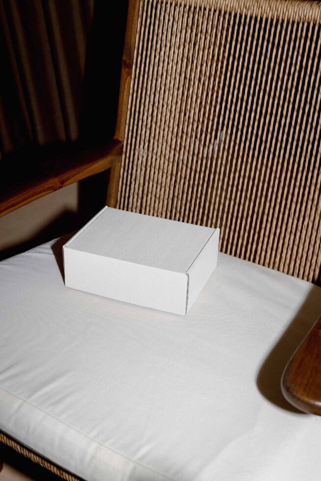 White box mockup on minimal table with wood chair, ribbed wall backdrop