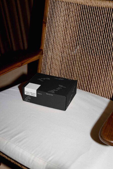 Black luxury box mockup with white label detail on minimal table setup with wood chair
