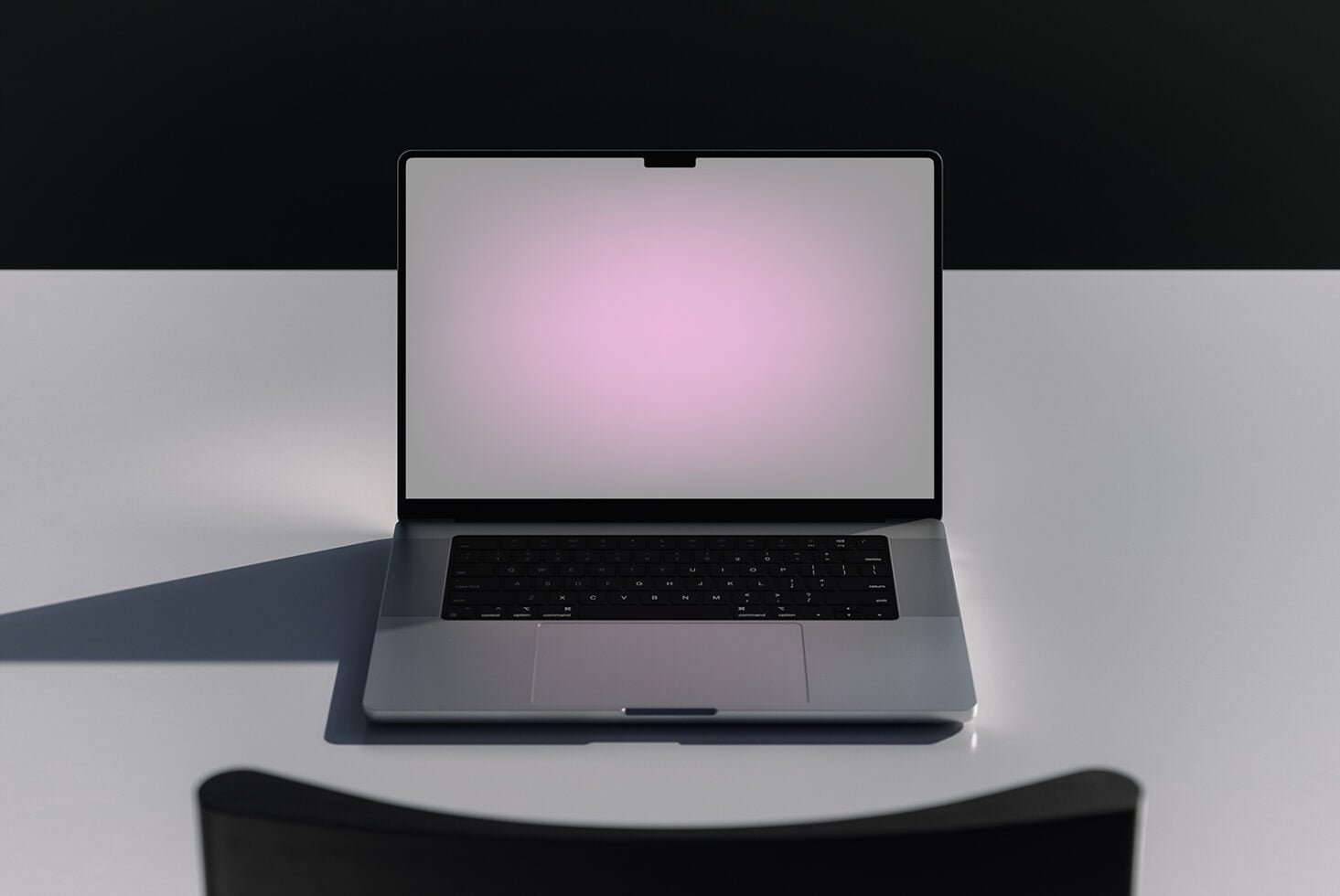 Open silver laptop with pink gradient screen displayed on white surface with dark backdrop