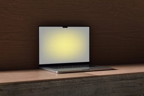 Laptop mockup sitting on wooden table with dark wood background, screen glowing