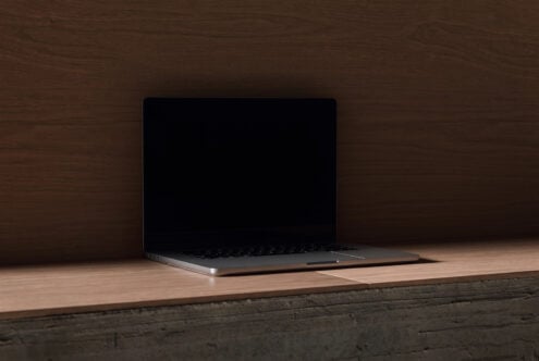 Sleek laptop mockup sitting on warm wood surface with dark textured wall background