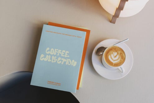 Blue Coffee Collection notebook stacked with orange spine next to latte cup with latte art